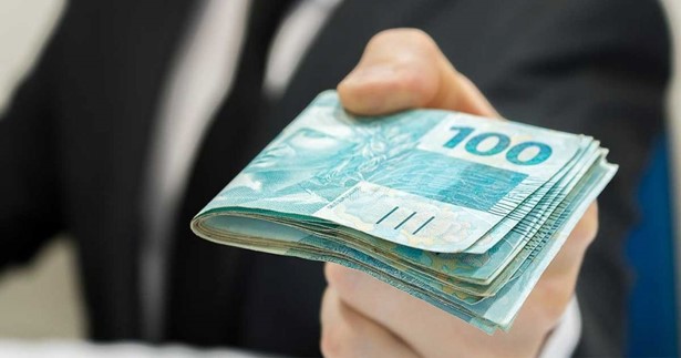 Mão segurando notas de 100 reais