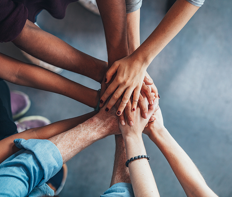 Stack of hands showing unity Close up top view of young people putting their hands together. Friends with stack of hands showing unity.